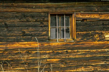 Eski ahşap bir evin duvarında küçük bir pencere.