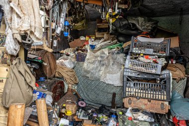 Sibiu, Romanya - 2 Ağustos 2025 dağınık atölye, çeşitli eşyalarla dolu dağınık, loş bir depo. Zemin çeşitli malzemelerle kaplı.