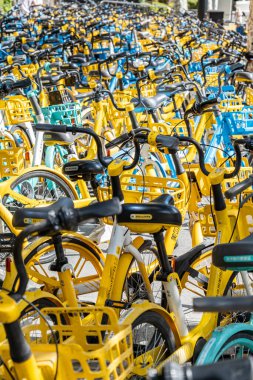Şangay, Çin - 25 Eylül 2025 bisiklet paylaşım sistemi bisikletleri, Şangay, Çin. Güneşli bir günde düzgün park edilmiş sarı ve mavi renkli bisiklet sıraları.