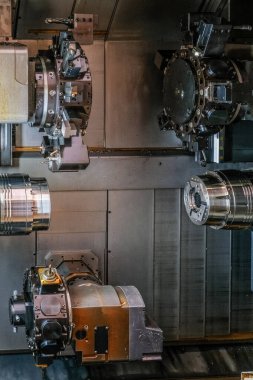 Çok sayıda civata ve dişlilere sahip çoklu dairesel metal bileşenlerden oluşan karmaşık bir endüstriyel makine. Makine parçaları ağırlıklı olarak siyah ve gri, gümüş aksanlı.