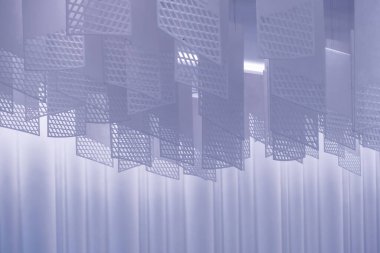 Tavandan sarkan bir dizi geometrik desenli kağıt fener. Fenerler, şebeke benzeri bir dizaynla dikdörtgen şeklindedir. Beyaz, hafif ışıklandırılmış arka plan üzerine karmaşık gölgeler bırakırlar.