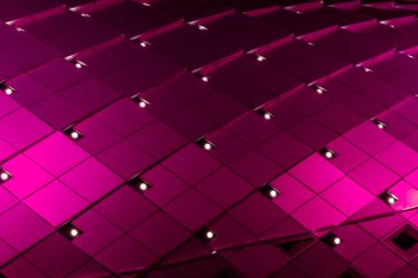 Geometrik, metalik yüzey kare karolardan oluşan bir şebeke deseni içeriyor. Fayanslar dinamik, soyut ve görsel olarak çarpıcı modern mimari bir cephe oluşturan canlı ışıklandırmayla aydınlatılıyor.