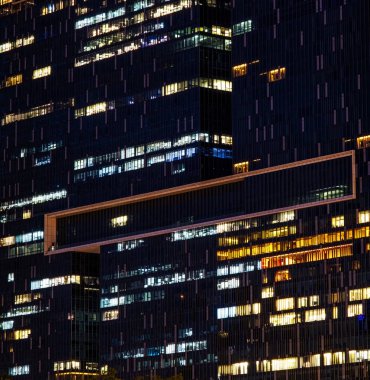 Geceleri çok katlı ofis binasında fazla mesai yapan işçiler var. Geç saatte ofiste. ışıklandırma ve çalışan insanlar