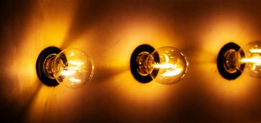 Altın sarısı bir duvara monte edilmiş vintage tarzı parlak ampuller.