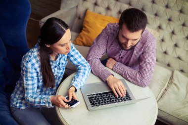 Genç çift dizüstü bilgisayar kullanıyor