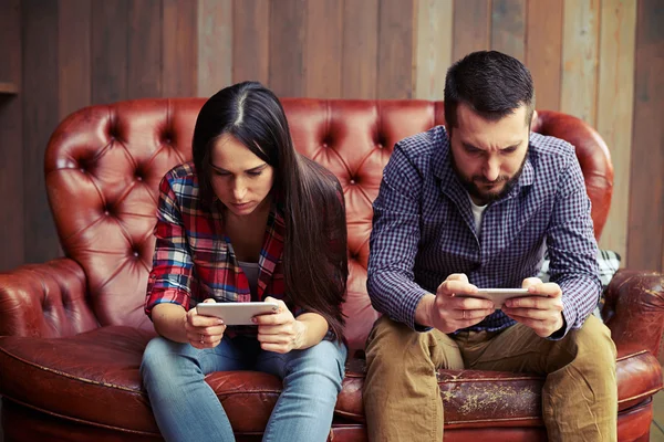 Donna e uomo seduti sul divano con smartphone — Foto Stock