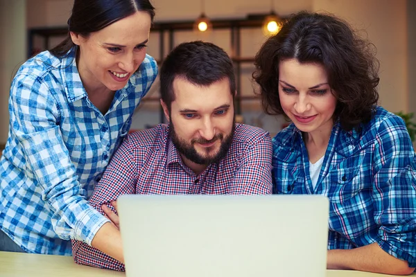 Cheerful team mates working with laptop — Stock Photo, Image