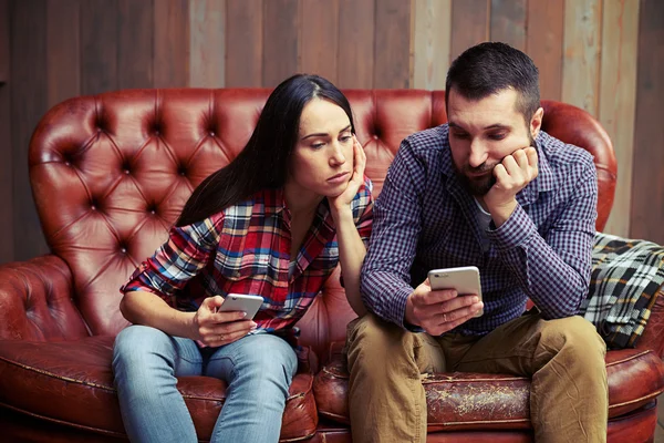 Menschen, die auf der Couch sitzen und auf den Phon schauen — Stockfoto