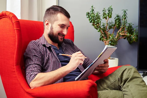 Mann hält Bleistift mit Notizblock zu Hause — Stockfoto