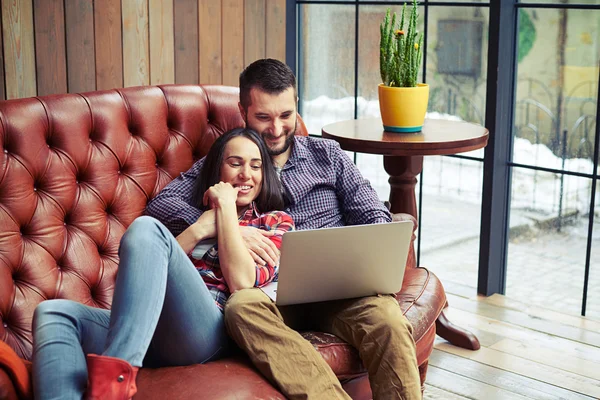 Молодая пара отдыхает на диване с ноутбуком — стоковое фото