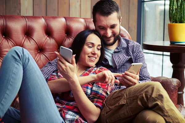 Par vilandes på soffan och titta på smartphone — Stockfoto