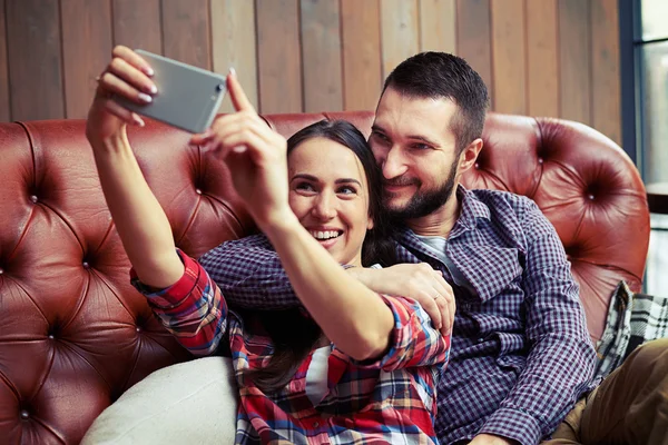 Kanepede oturan ve selfie fotoğraf çekimi bir çift — Stok fotoğraf