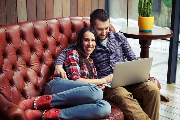 Paret sitter på soffan och använder bärbar dator hemma — Stockfoto