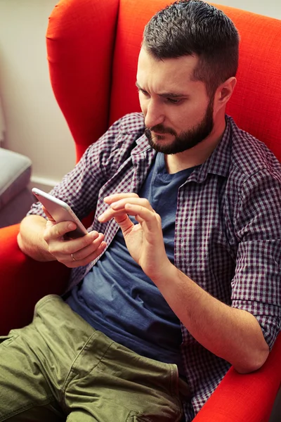 Man op de stoel zitten en via zijn smartphone — Stockfoto