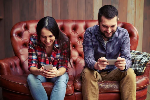 Homem sorridente e mulher usando smartphones — Fotografia de Stock