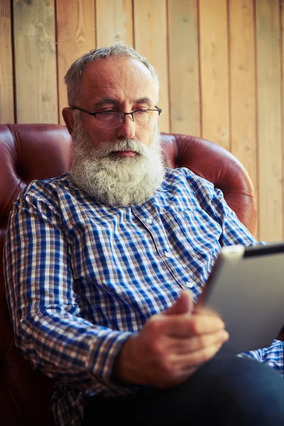 Vousatý muž sedí na pohovce a použití počítače tablet pc — Stock fotografie