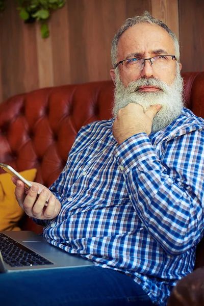 Muž drží smartphone a přemýšlet o něčem — Stock fotografie