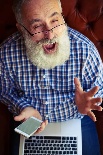 Aufgeregter alter Mann mit Laptop und Smartphone — Stockfoto