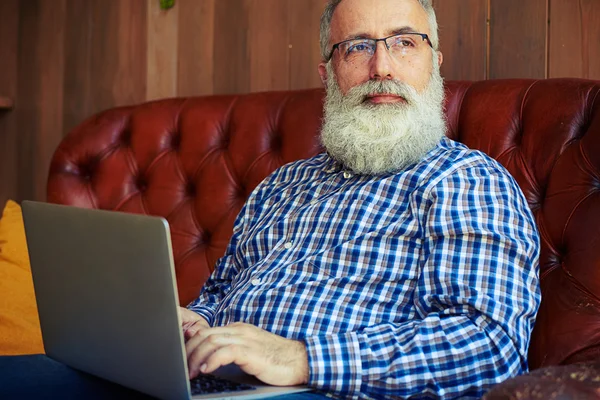 Man met laptop zitten en kijken naar venster — Stockfoto