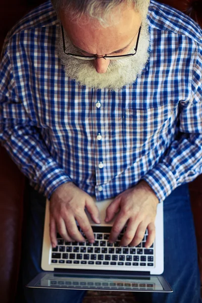 Senior man te typen op laptop — Stockfoto