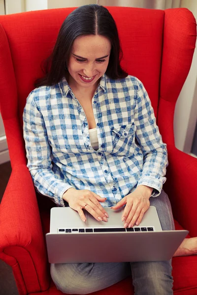Smiley νεαρή γυναίκα χρησιμοποιώντας φορητό υπολογιστή στο σπίτι — Φωτογραφία Αρχείου