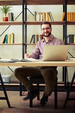 Genç adam bir sandalyede oturuyor ve not alma