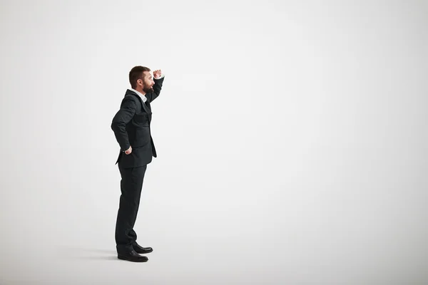 Un hombre barbudo con un traje de negocios negro mira a la distancia —  Fotos de Stock