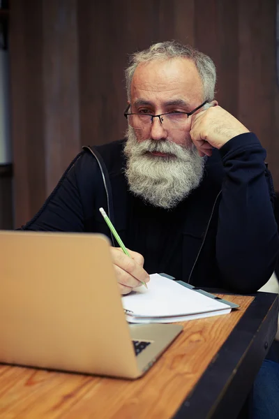 Attraktiva skäggiga senior arbetar på sin laptop — Stockfoto