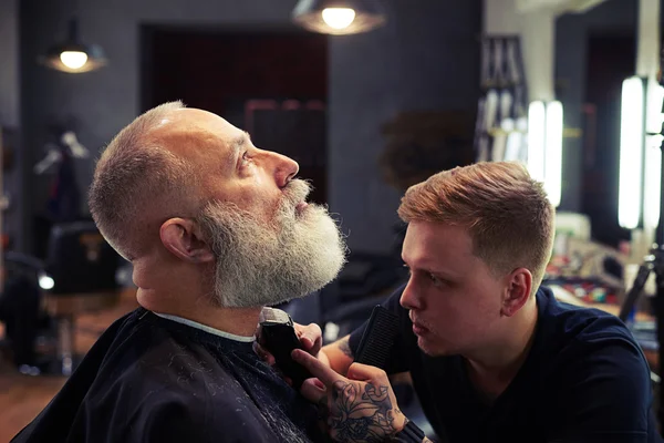 Barber making haircut to handsome attractive senior man — Stock Photo, Image