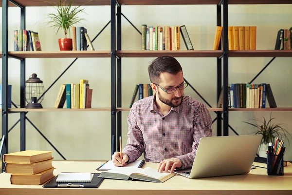 Empresario con las gafas reescribiendo de un libro y mirando un —  Fotos de Stock