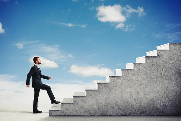 Man climbing concrete stairs in a light cloudy sky — Stock Photo, Image