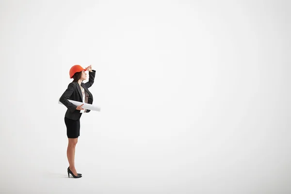 Mujer en traje formal y casco de construcción con planos — Foto de Stock