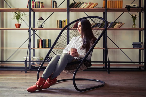 Mujer sentada en una silla de diseño y mirando hacia otro lado — Foto de Stock