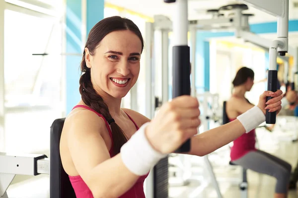 Girl is working out on butterfly machine in gym — Stock Photo, Image