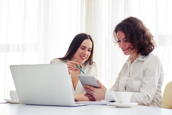 Duas mulheres bonitas trabalhando juntas com gadgets no escritório — Fotografia de Stock