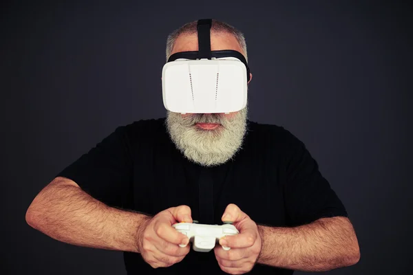 Senior man spelar på joysticken bär Hi-Tech VR headset — Stockfoto