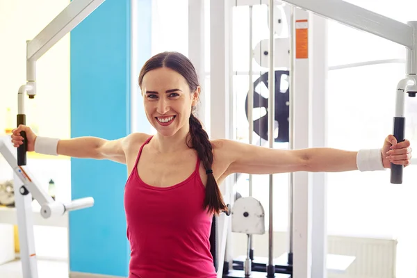 Mujer está haciendo ejercicio en la máquina de mariposas en el gimnasio — Foto de Stock