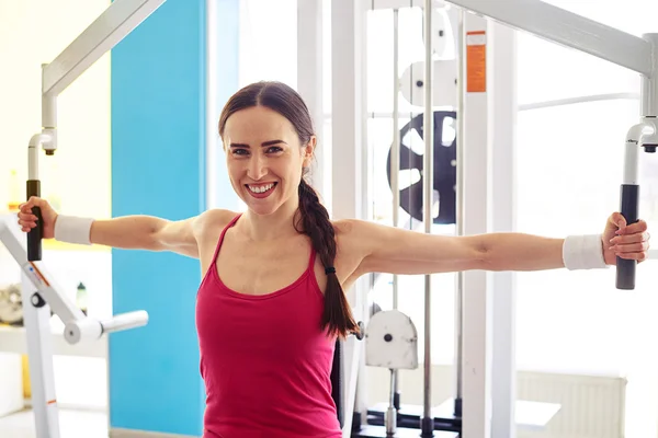 Woman is working out on butterfly machine in gym — ストック写真