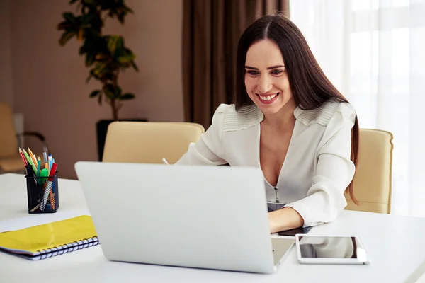 Junge Brünette arbeitet an ihrem Notizbuch im modernen Büro — Stockfoto