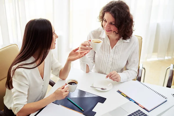 Dos mujeres hablando de algo y tomando café en el trabajo —  Fotos de Stock