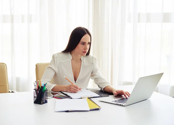 Vrouw die op haar laptop op kantoor werkt — Stockfoto