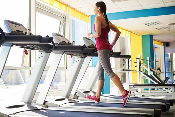 Girl in sportswear is running on a treadmill — Stock Photo, Image
