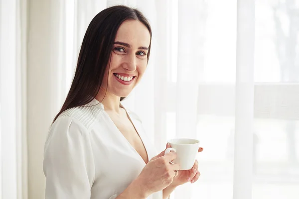 Mujer sonriente se para y sostiene el café — Foto de Stock