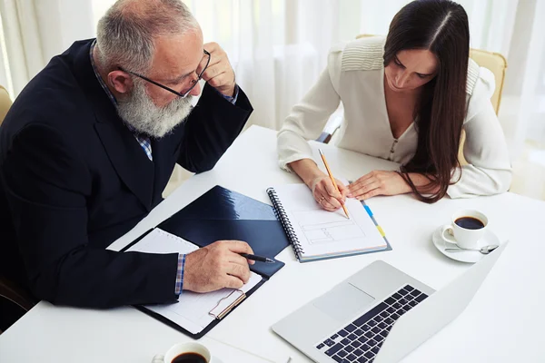 Businessman and businesswoman discussing documents and ideas — Stock Photo, Image