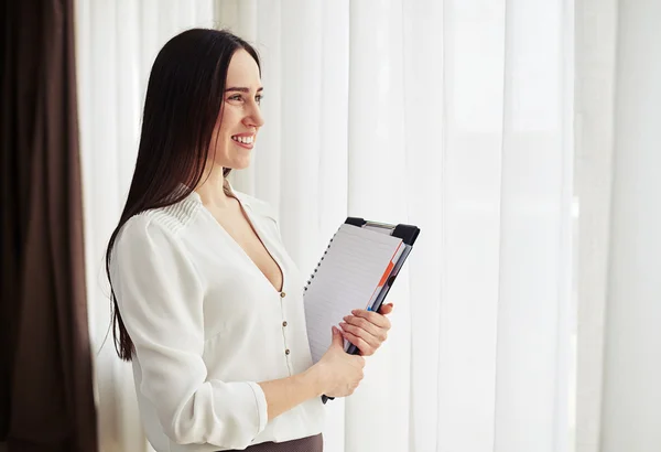 Woman looks aside and holding notepad — Stock Photo, Image