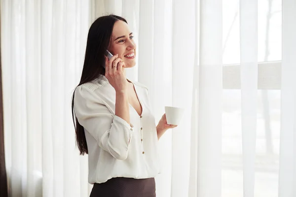 Ung kvinna håller kaffe och prata i telefon — Stockfoto