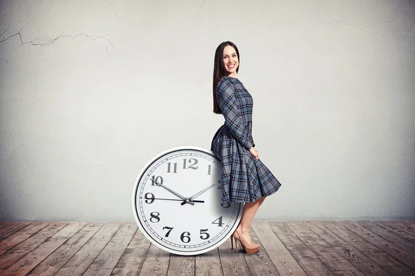 Una mujer está sentada en el reloj grande —  Fotos de Stock