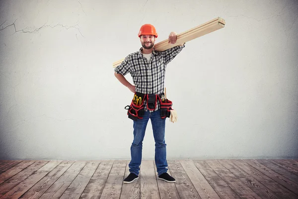 A workman with wooden boards on his shoulder — Stock Photo, Image