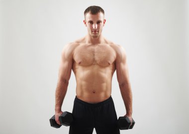 Beyaz arka plan üzerinde çıplak göğüslü atletik adam dumbbell tutan