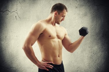 Çatlak duvar üzerinde dumbbell esneme pazı ile adam